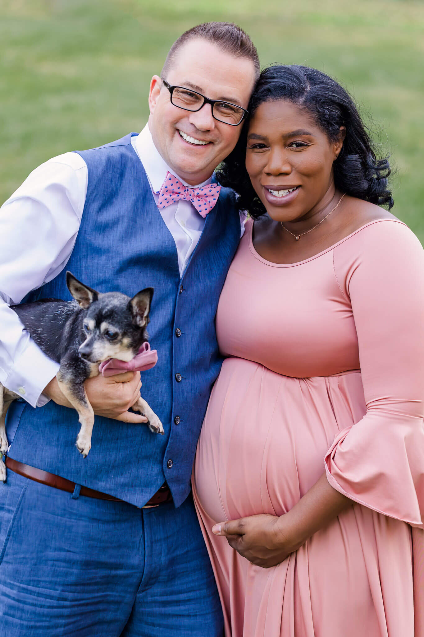 A happy couple standing in a park in Alexandria in the fall during their maternity photo session.