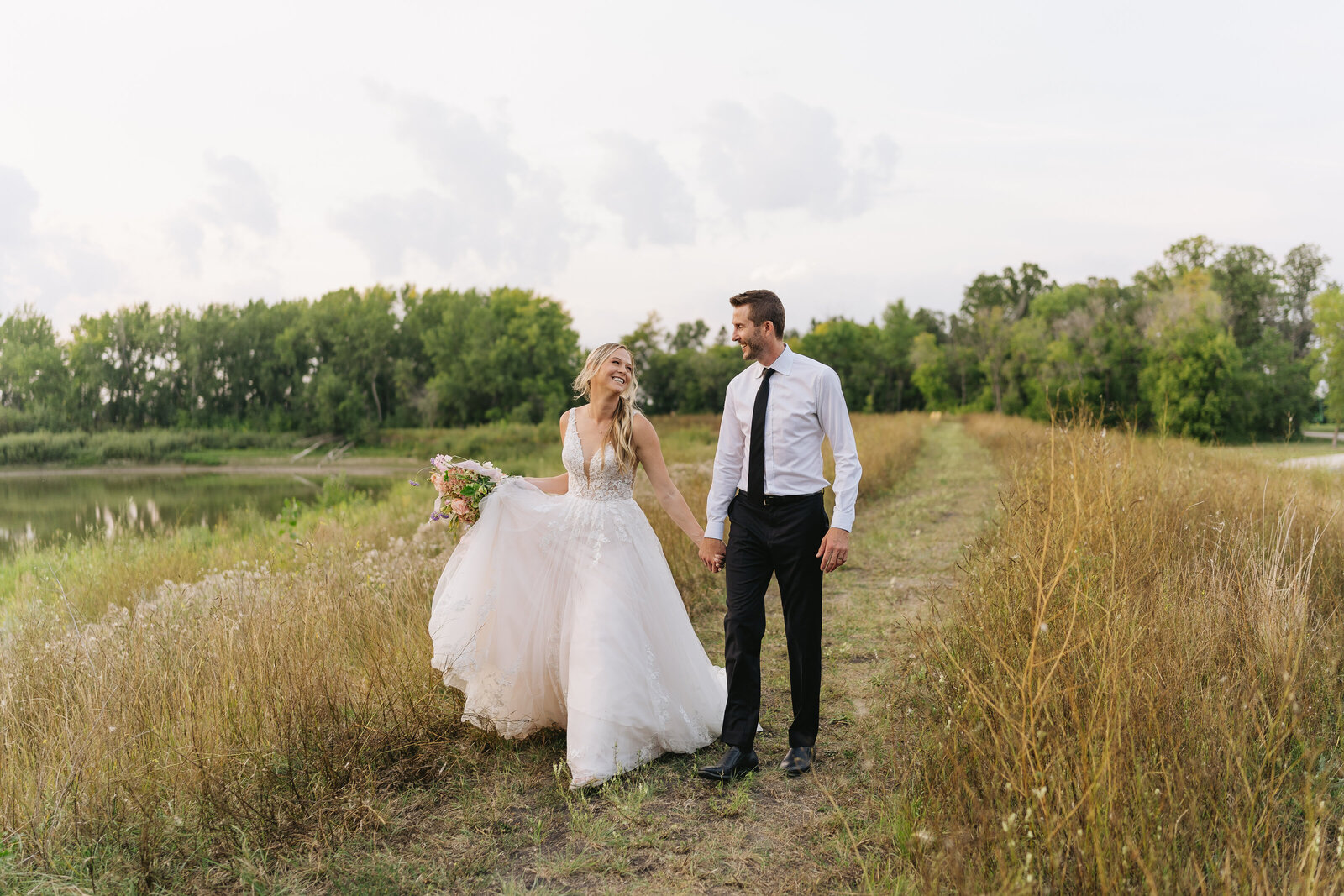 bride and groom kiss in front of arch full of greenery and white florals 