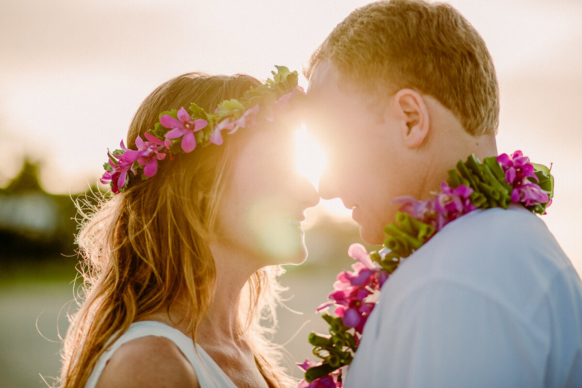 golden sunburst of light between couple on the beach forehead to forehead