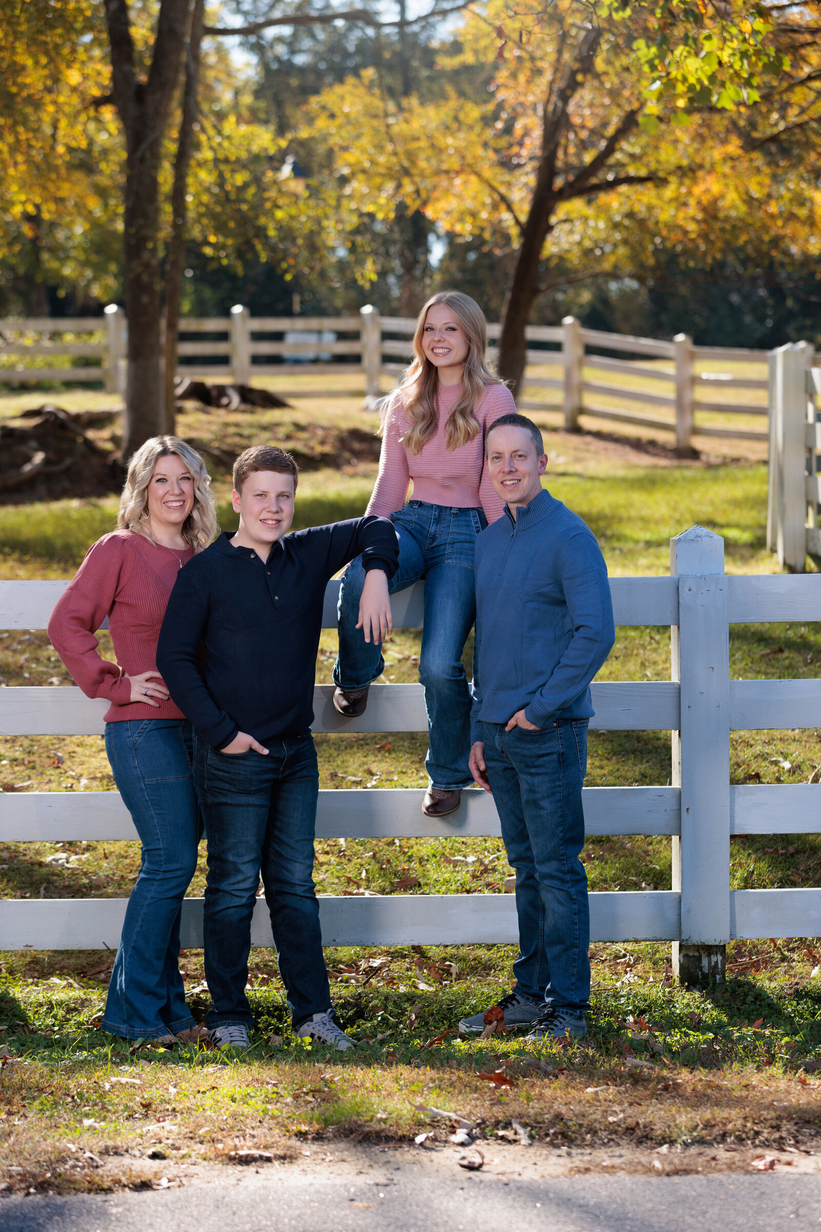 Family of four on a fence with the sun setting behind them in Raleigh NC.