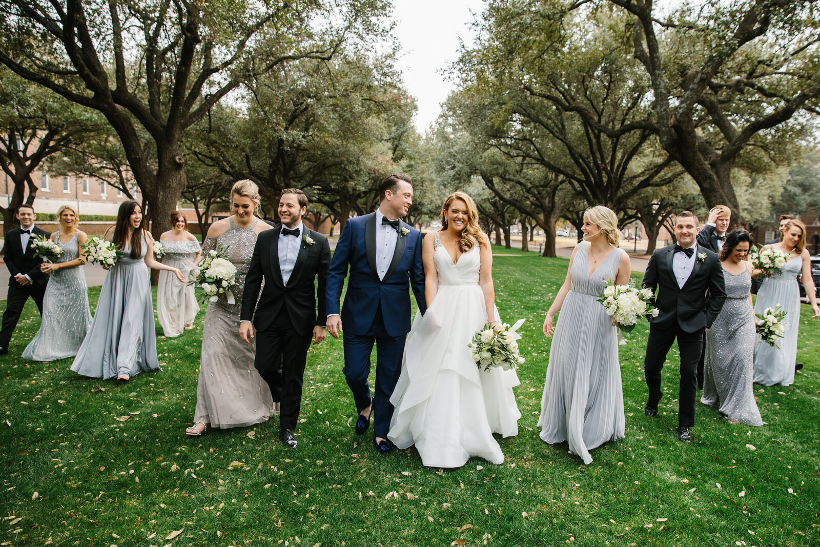 A group of bridesmaids and groomsmen walking in the grass at a Texas wedding.