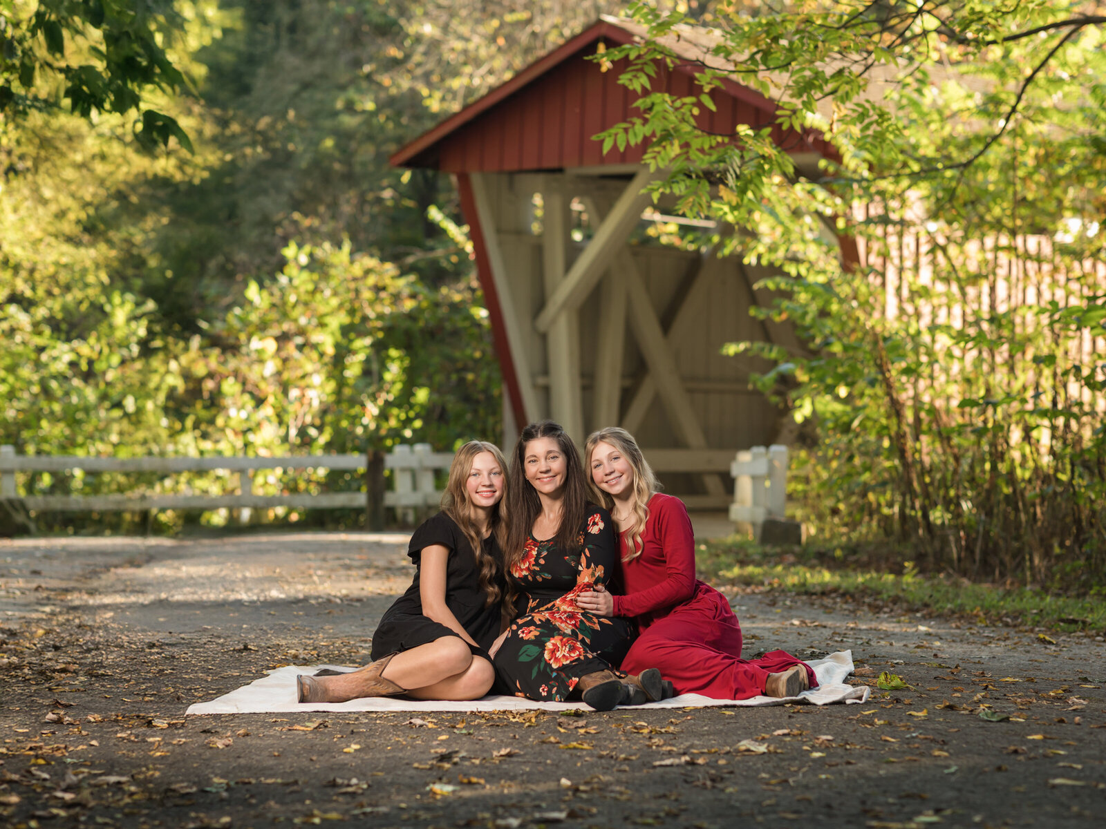 mom and two daughters sitting in from of Everrett Covered bridge cleveland family photography