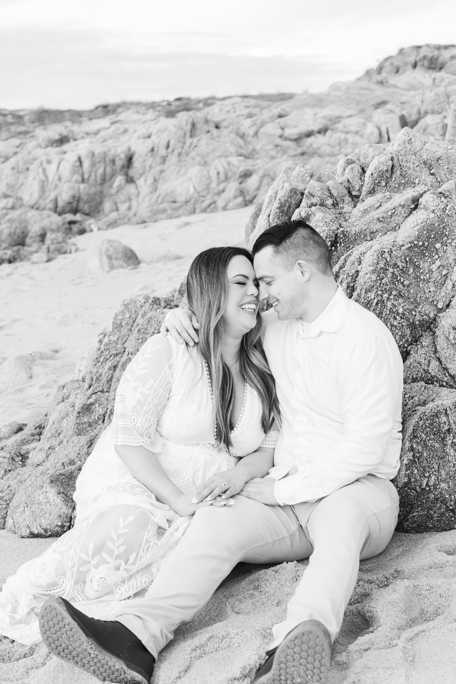 An engaged man and woman take photos on the beach in Pacific Grove, Monterey, California near Big Sur.