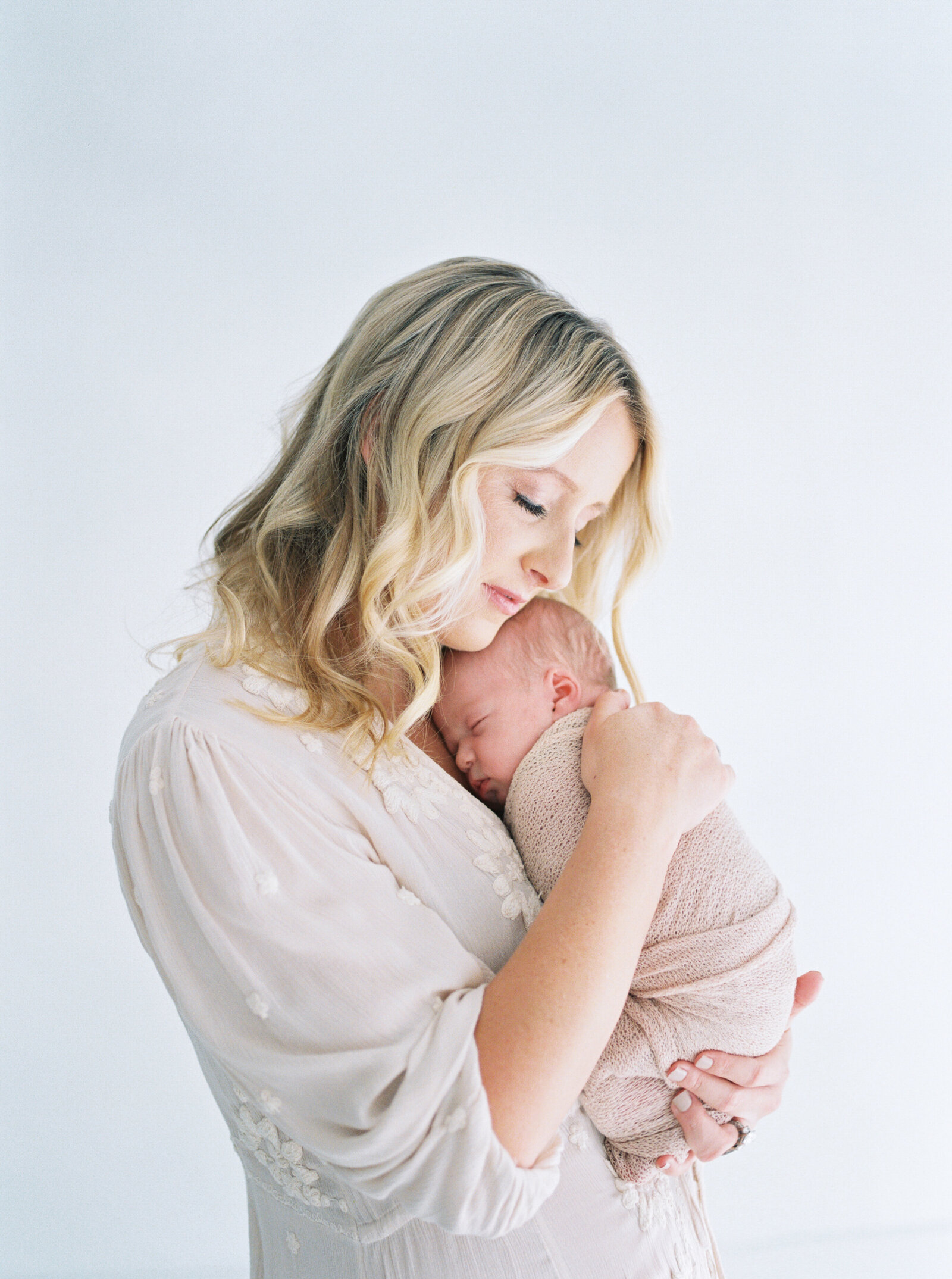 mama snuggling newborn baby in studio with Orlando baby photographer