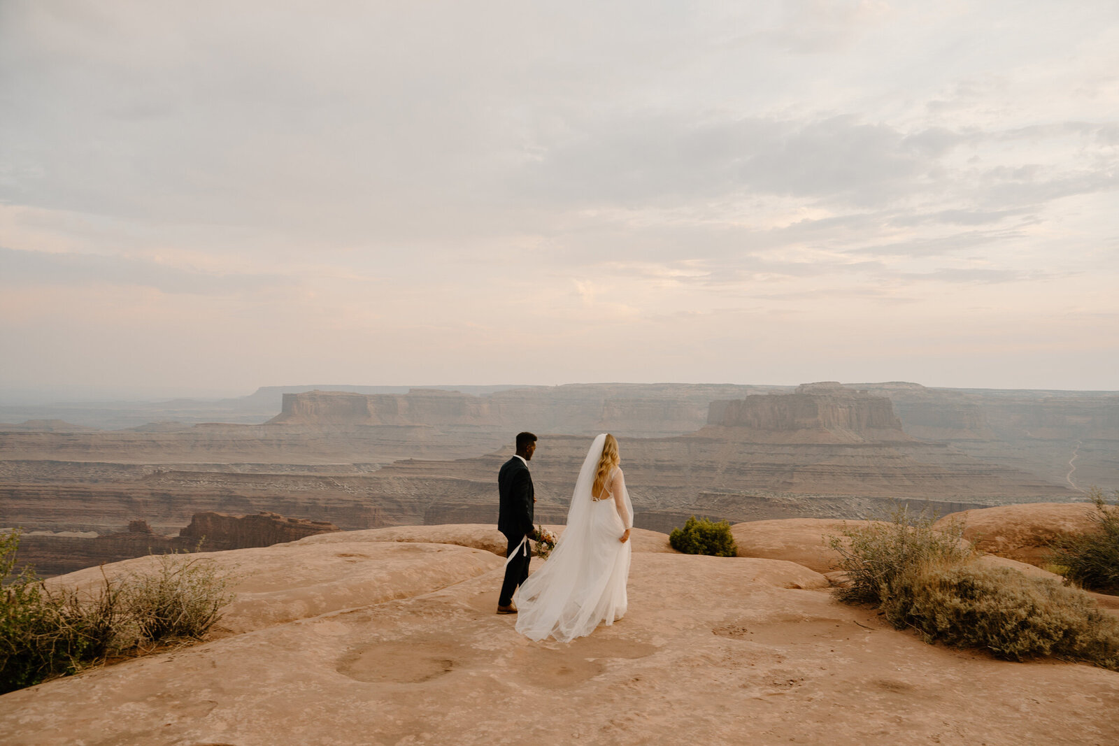 Mixed couple eloping at the dead horse state park in navy blue suit and gorgeous white wedding gown