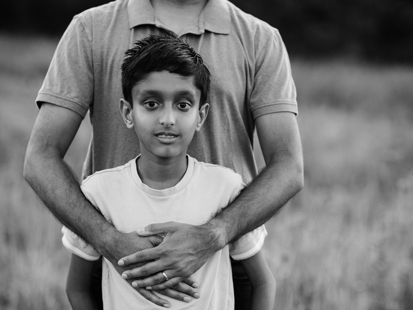 black and white photo of dads arms around son for family photoshoot 