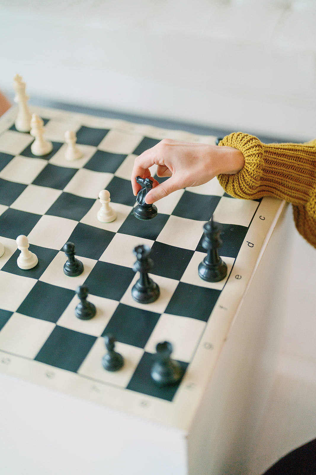 a chess table with a girls hand moving a piece