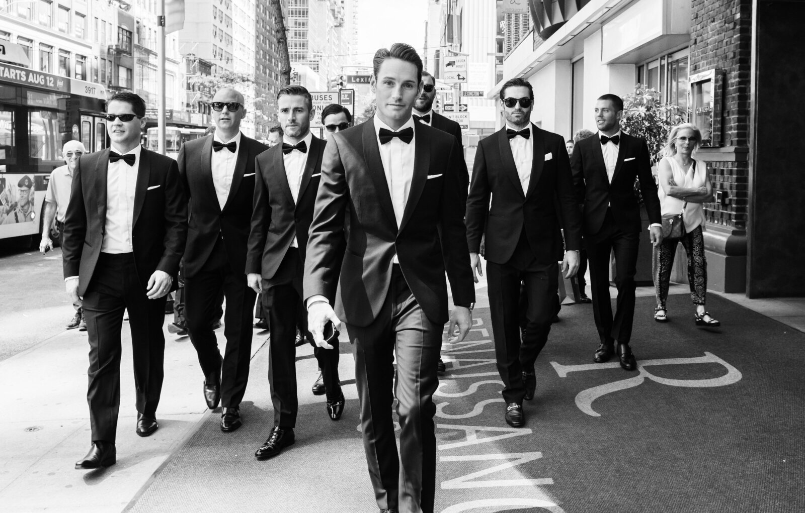 Black and white photo of groomsmen walking down sidewalk