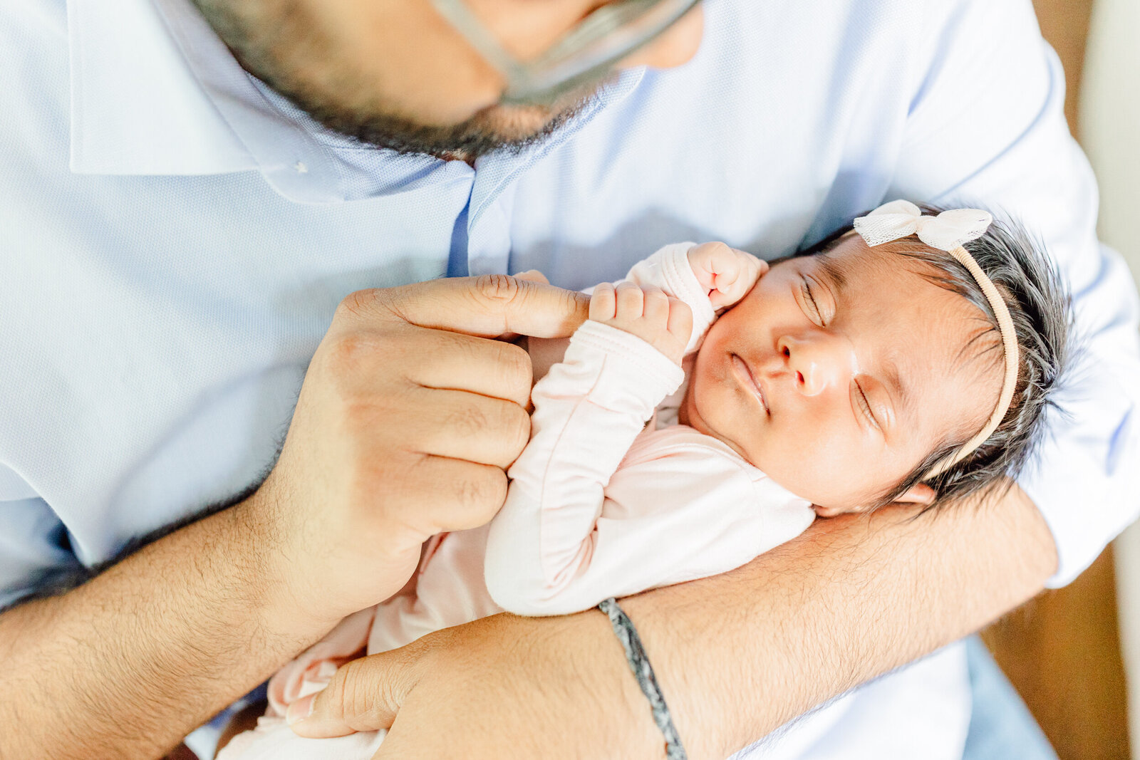 Closeup image of newborn daughter in dad's arms