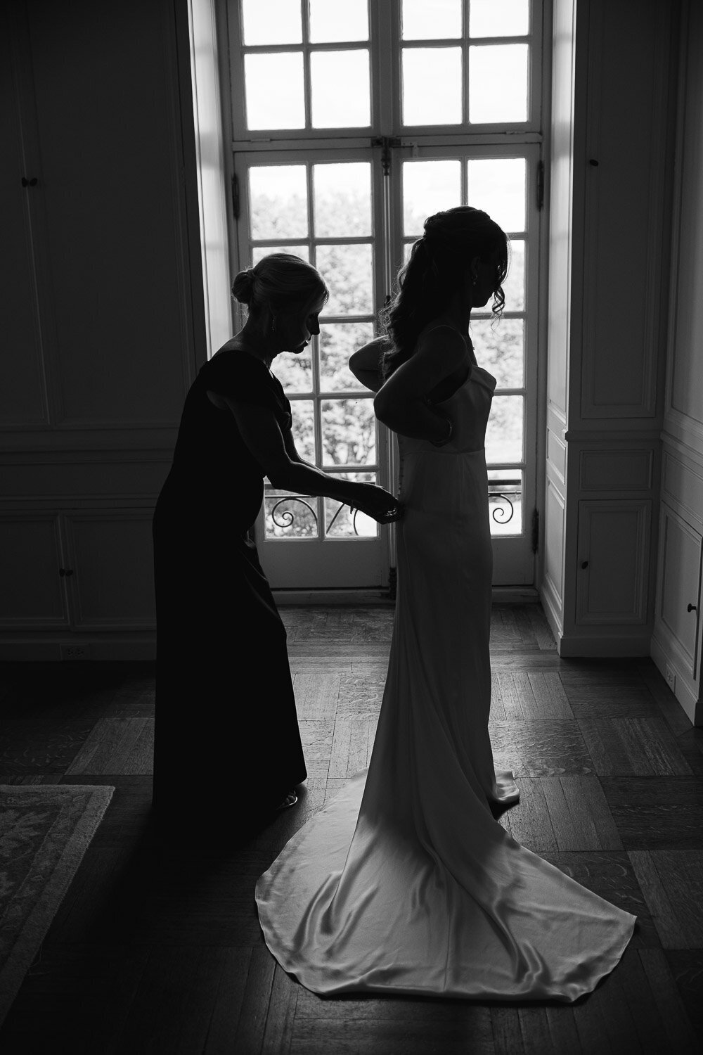 mom helping bride get into dress silhouette