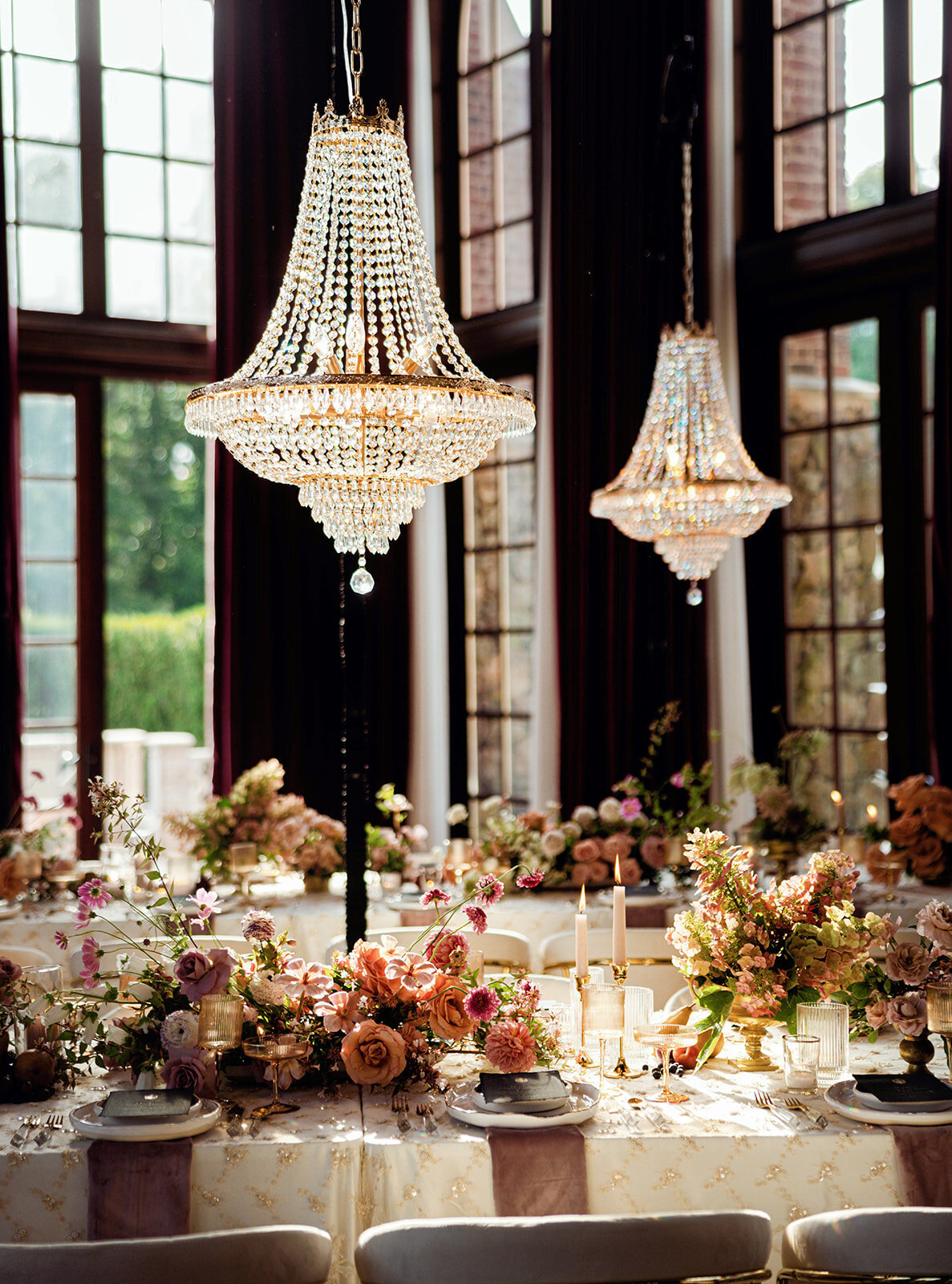 Crystal chandeliers above a reception table with blush and peach florals