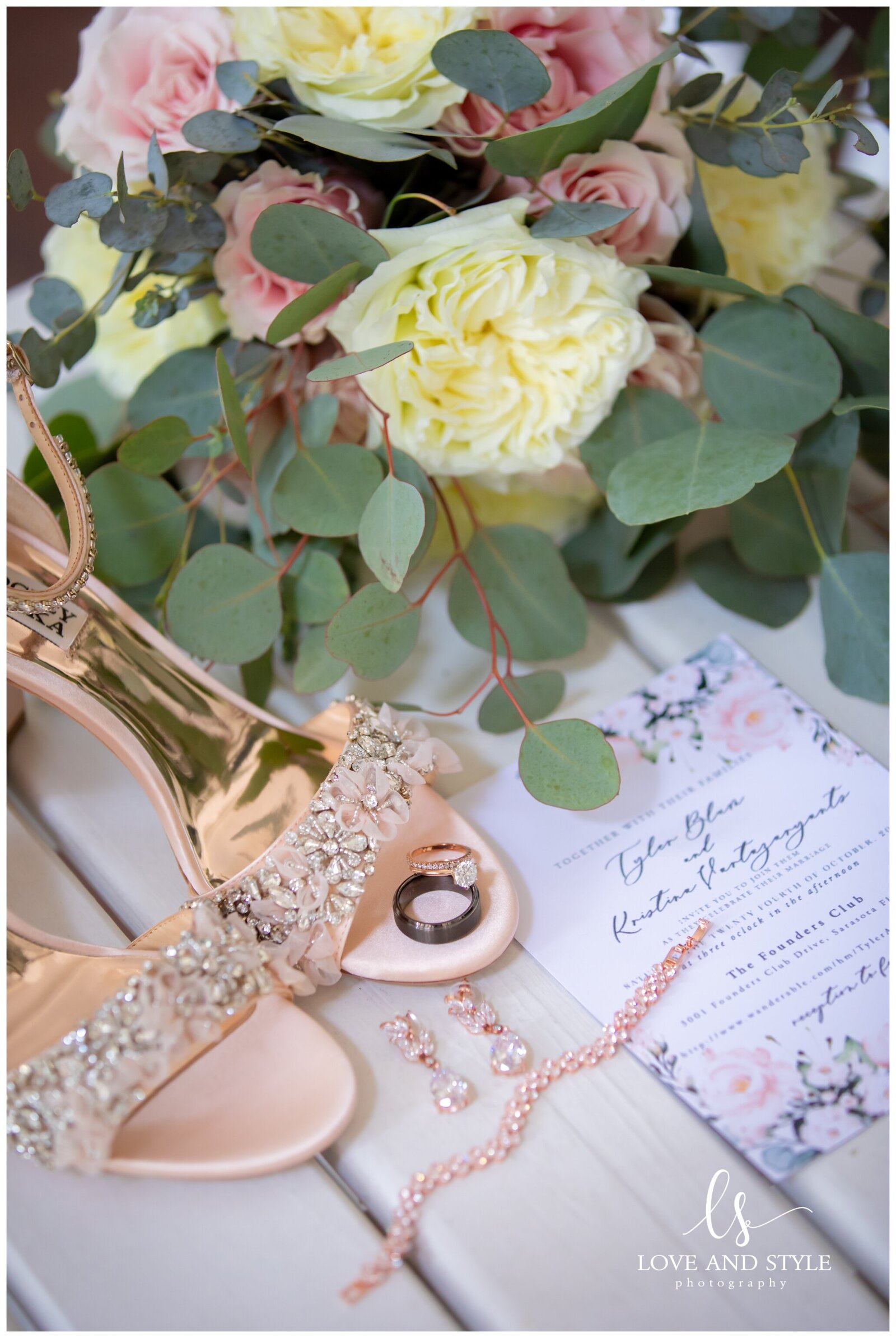 Detail shot of rose gold wedding shoes, invitation and brides jewelry
