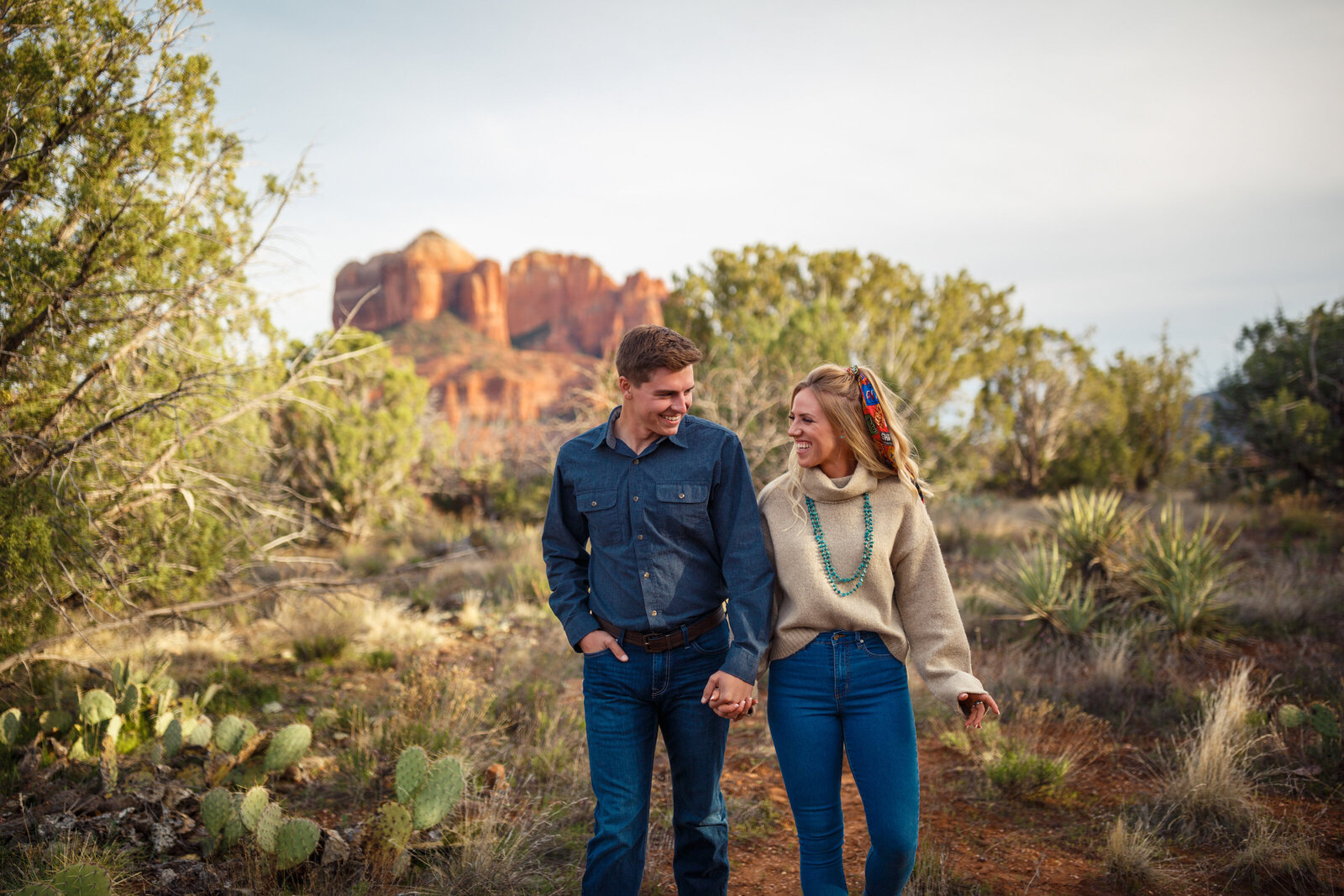 couple walking through sedona red rocks in front of cathedral rock