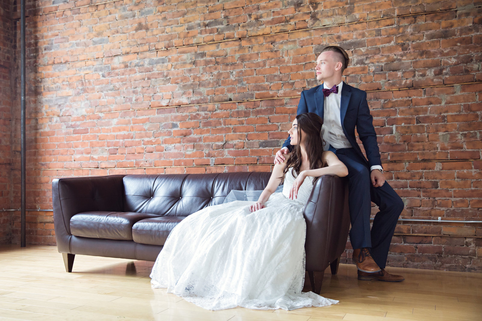 bride and groom sitting on couch brick wall