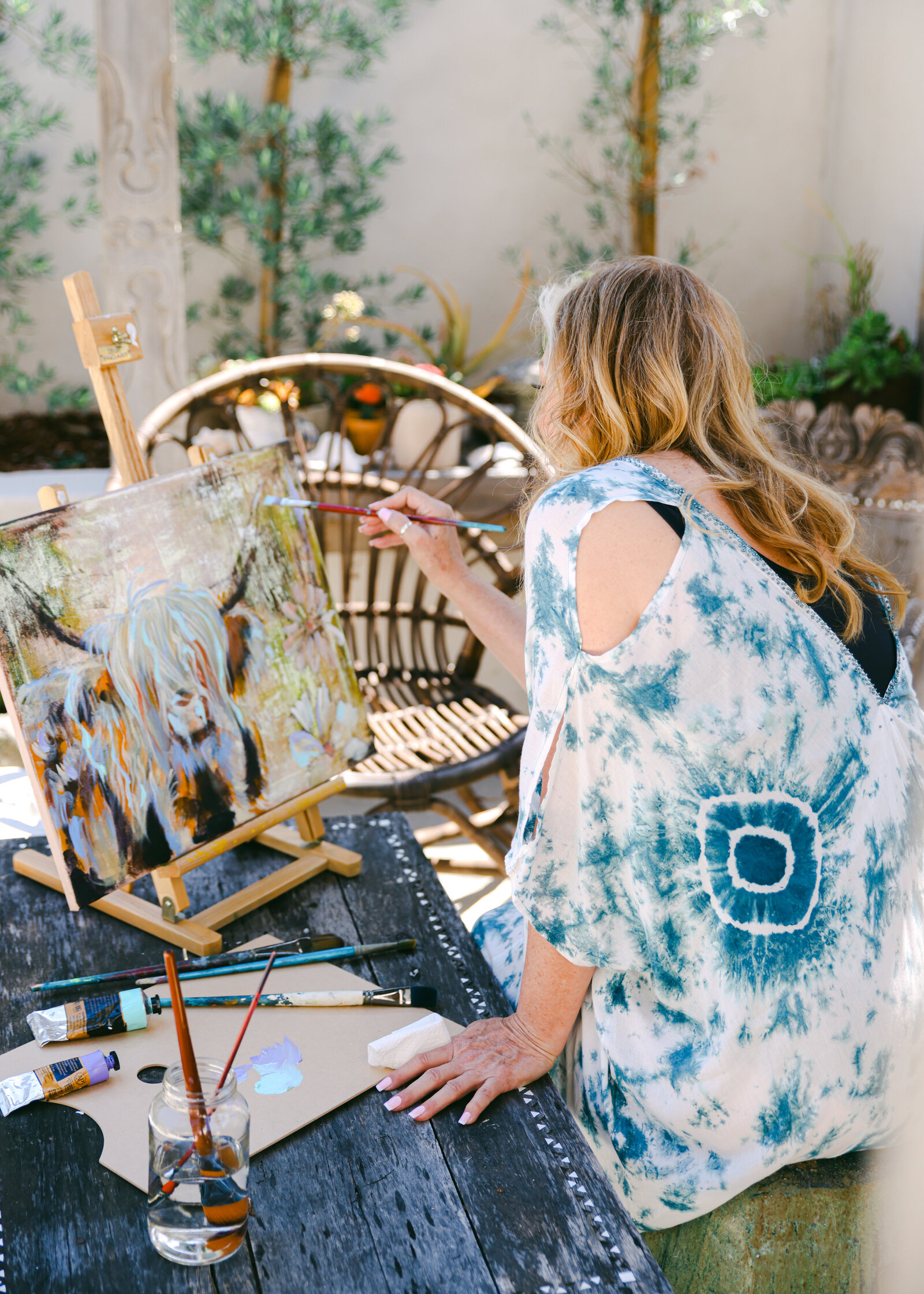 boho woman painting on easel in backyard southern california