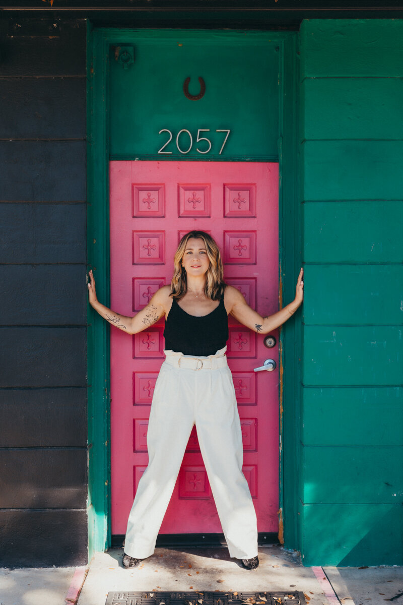 woman giving a power pose in a pink doorway in st pete fl