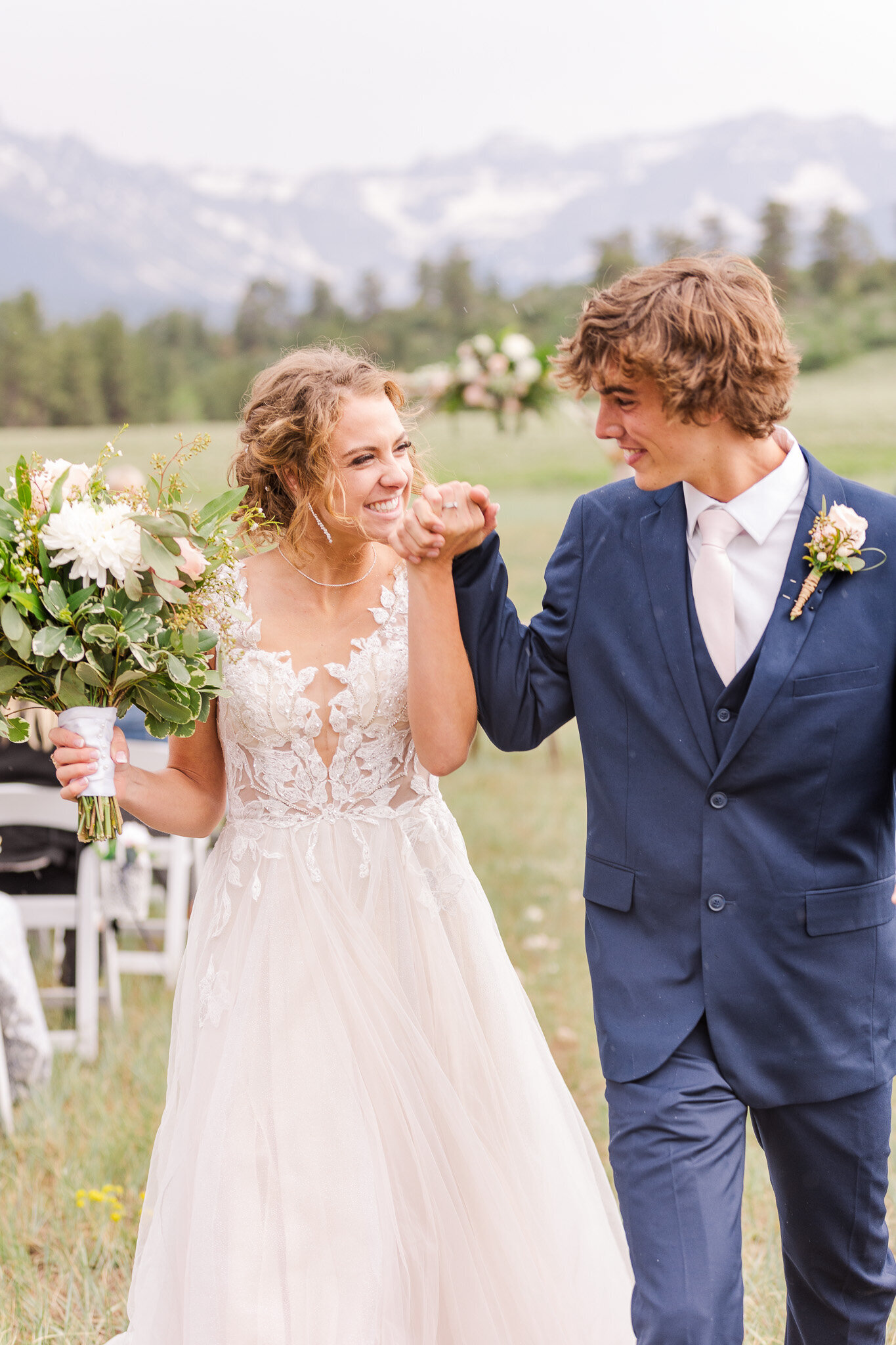 bride and groom smile at each other holdings hands