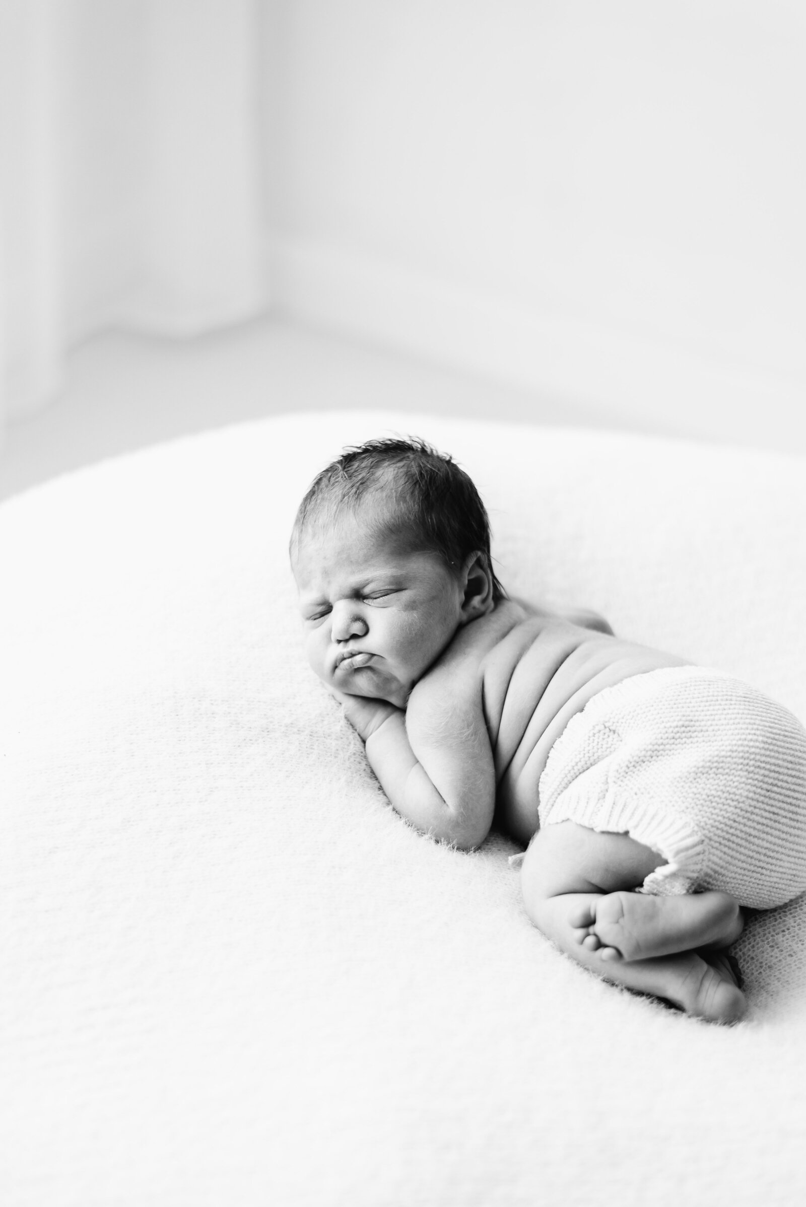 Baby girl sleeping on a white blanket at west sussex newborn photoshoot