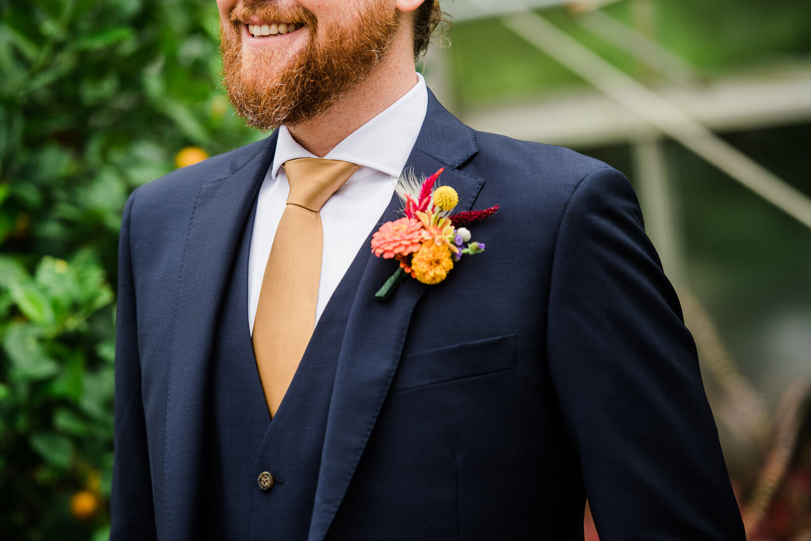 groom in blue suit with tan tie and colorful boutonniere