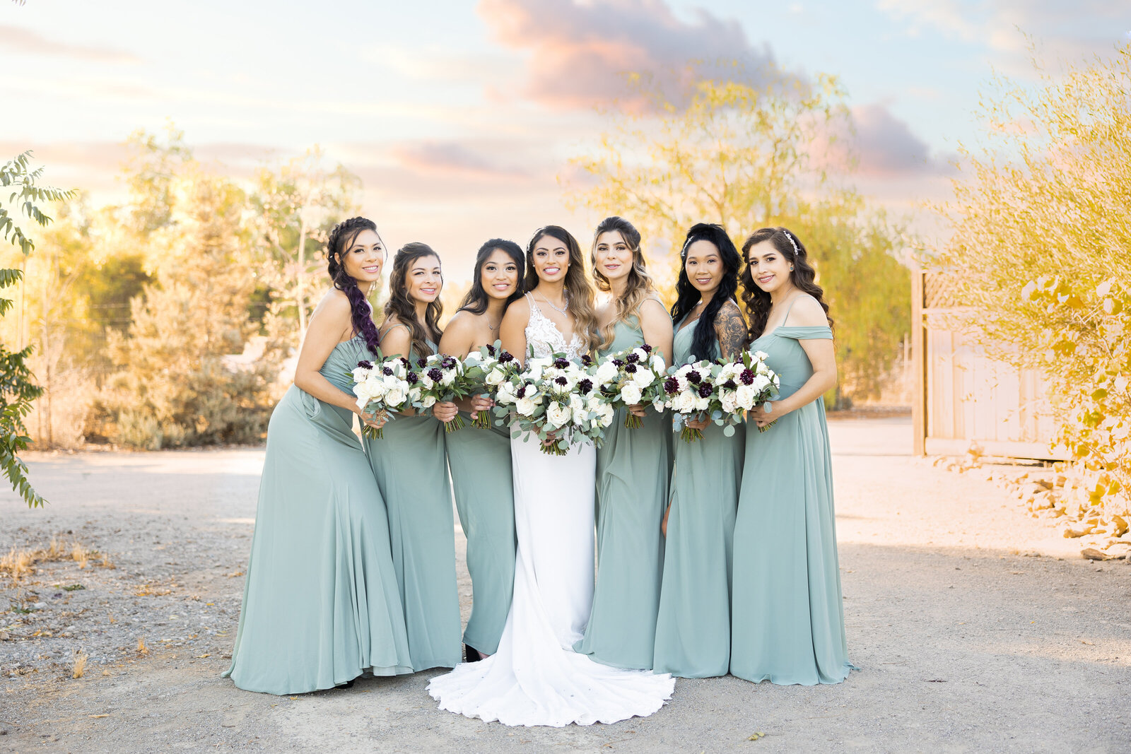 Bridesmaids wearing light green take a portrait together with bride in middle. Photo by wedding photographer in Sacramento, philippe studio pro.