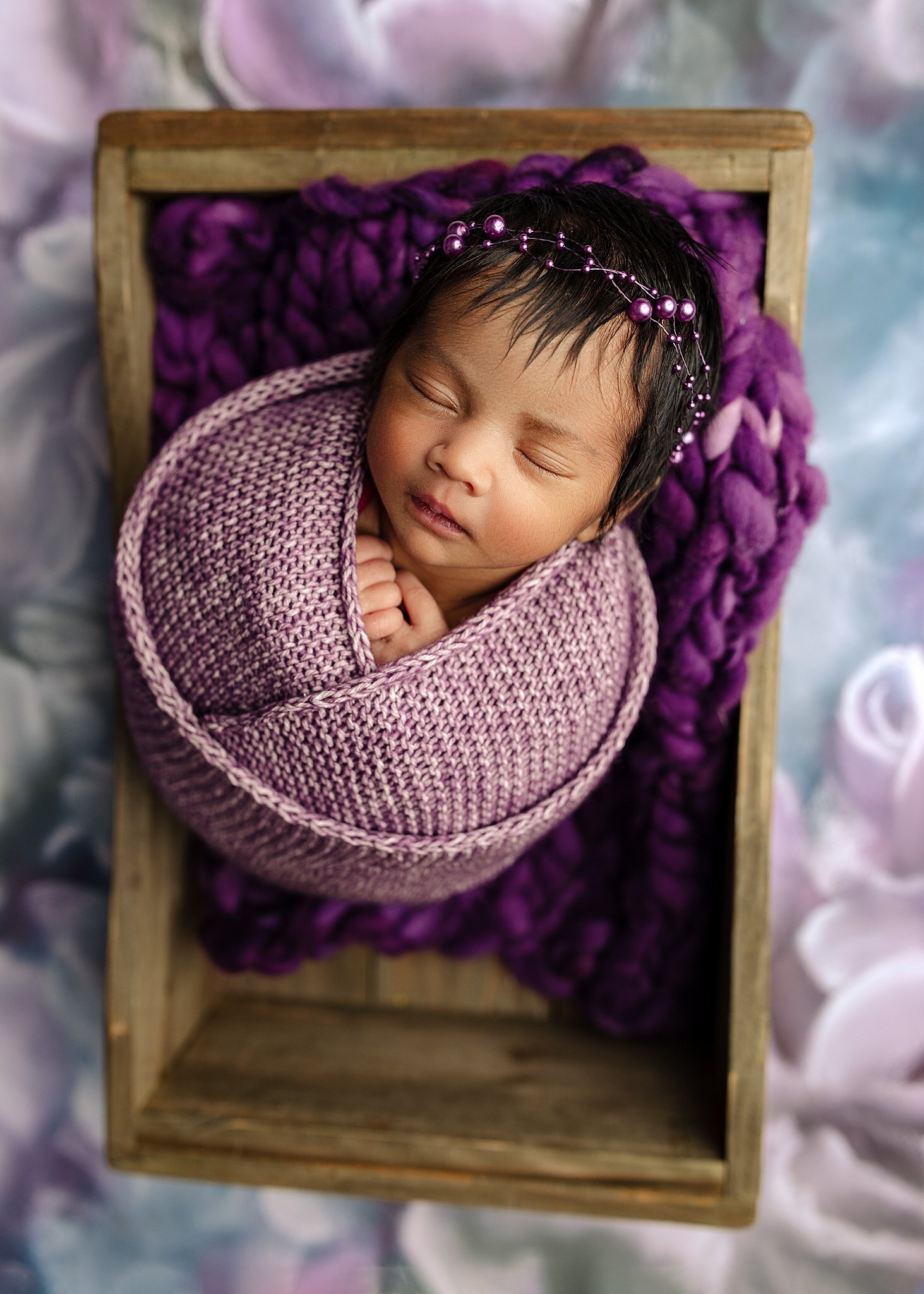 baby girl wrapped in purple in a box.