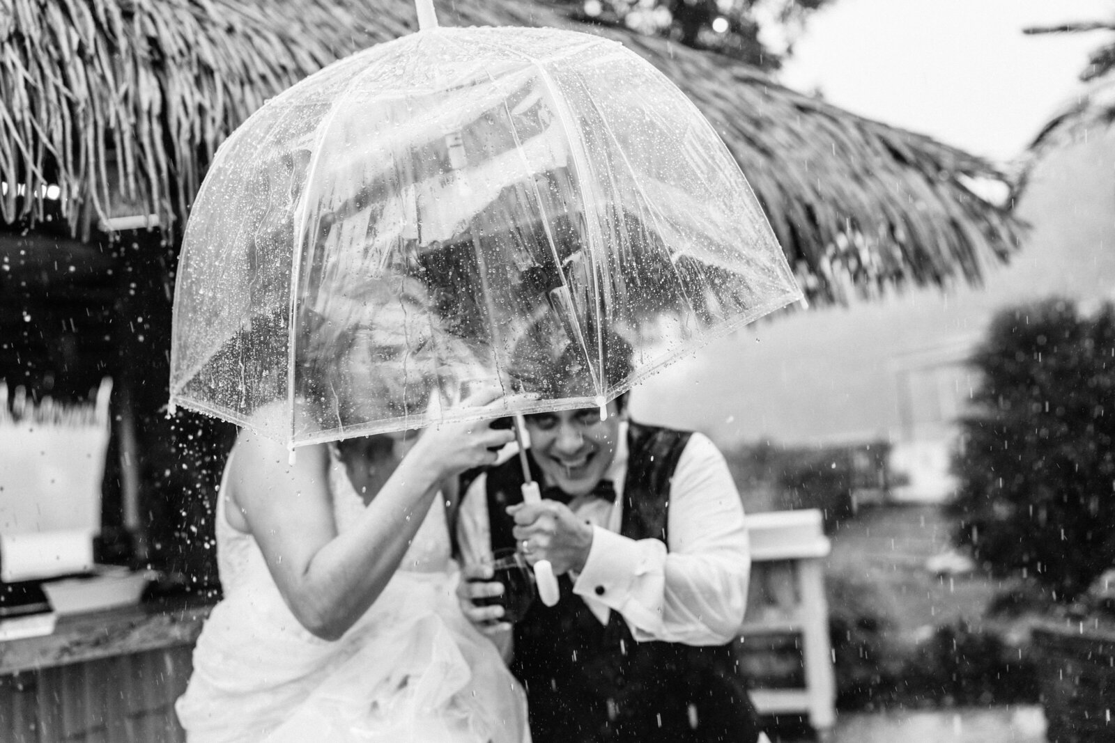 Bride and groom running in rain