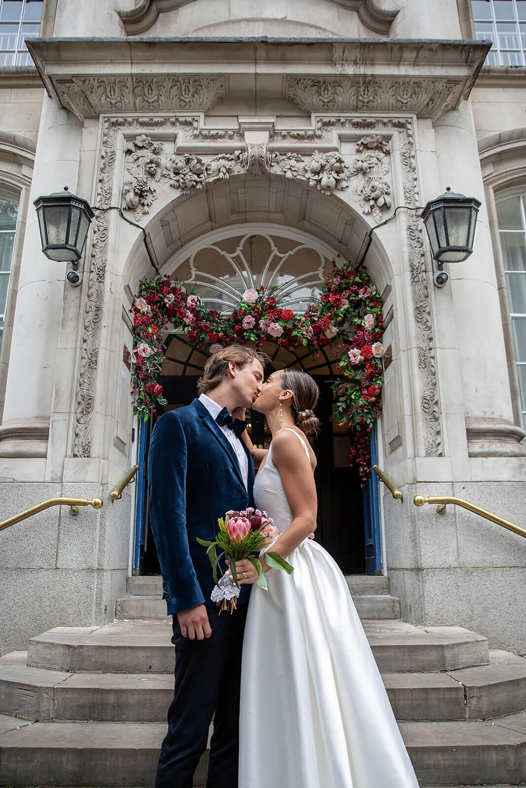 London bride and groom kissing on Chelsea Town Hall stairs