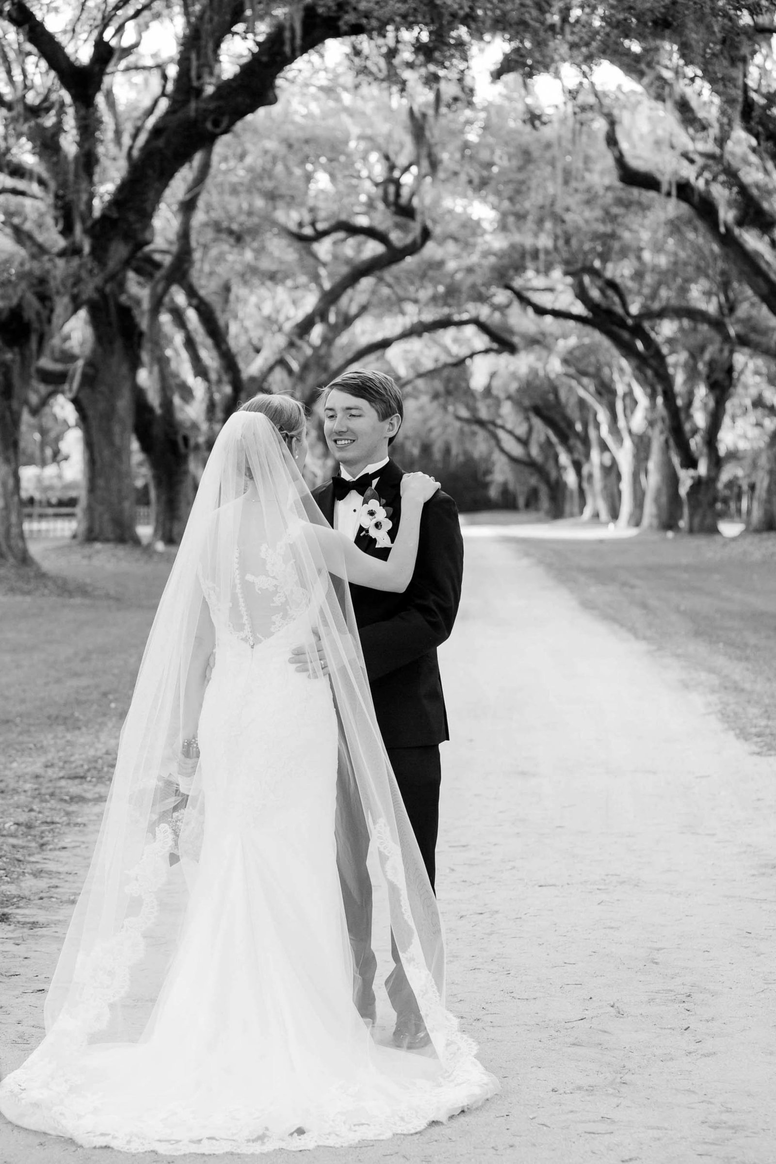 Bride and groom stand under avenue of oaks, Oakland Plantation, Mt Pleasant, South Carolina
