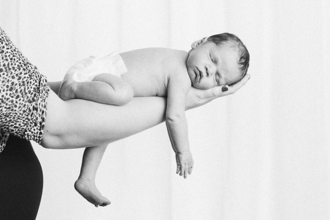 side profile black and white image of newborn baby sleeping with dangling arms