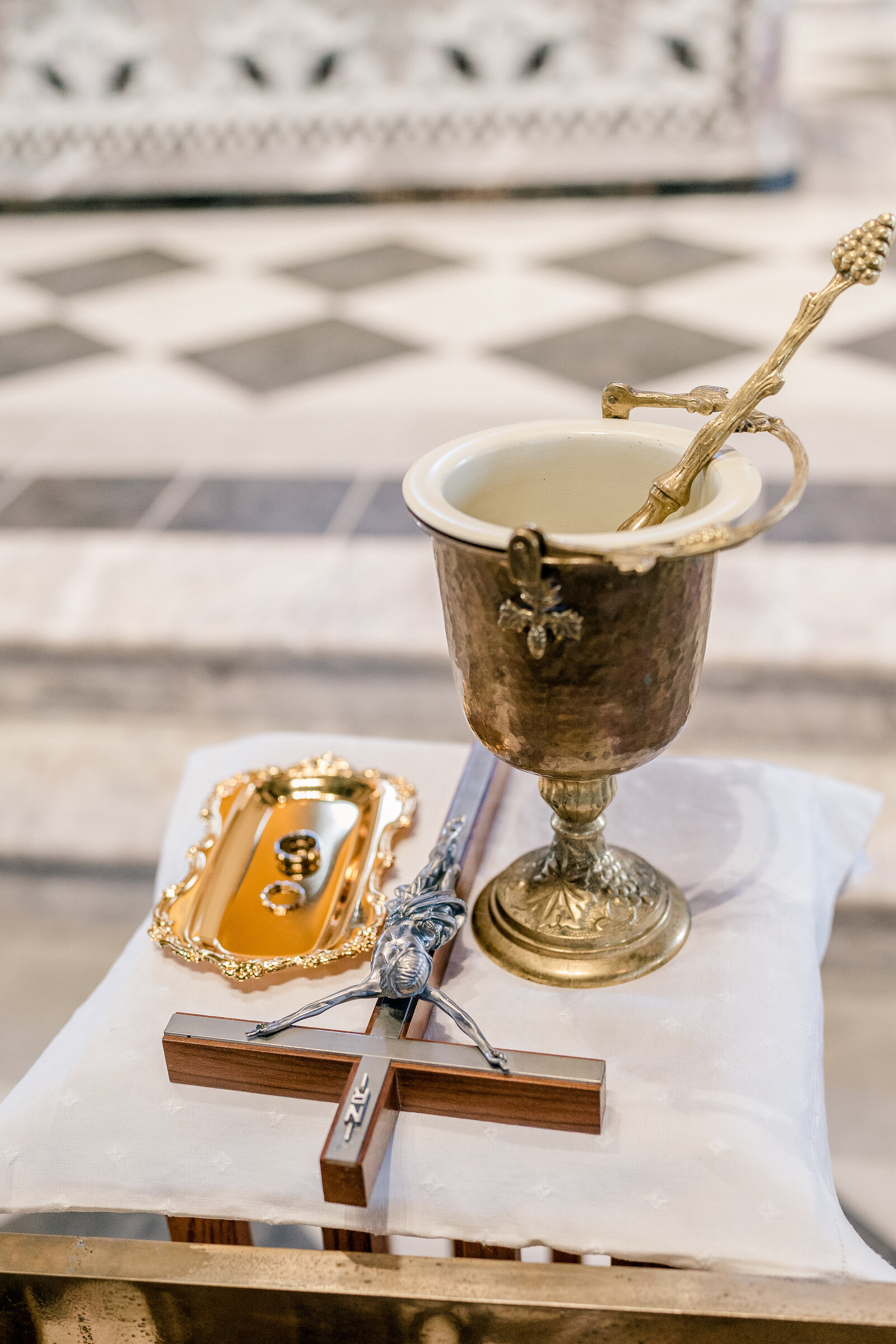 A small table set with holy water and a crucifix before a Catholic wedding at Corpus Christi Catholic Church in Loudoun County