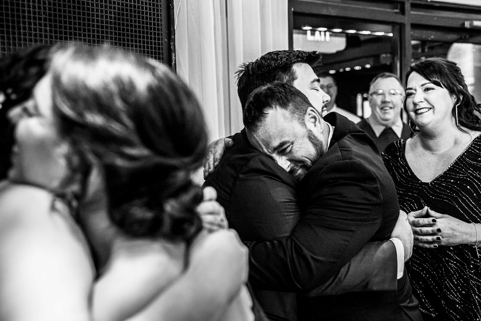 A groom hugs his father during the receiving line of a wedding.