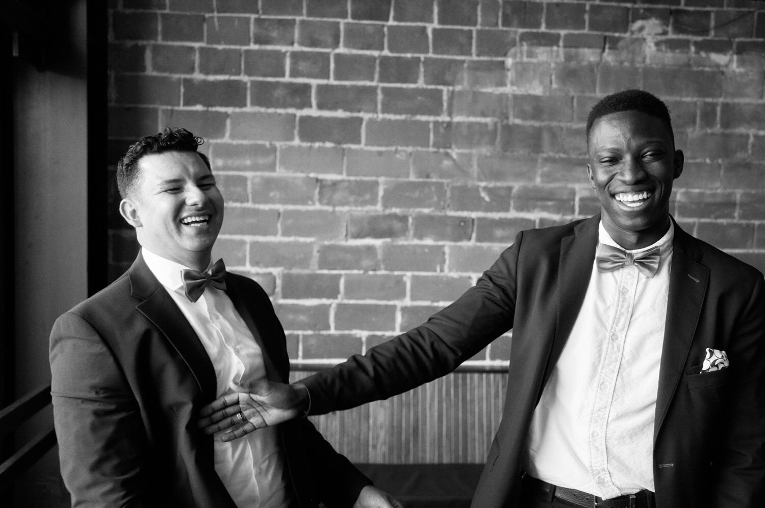 Two groomsmen laugh as they push each other