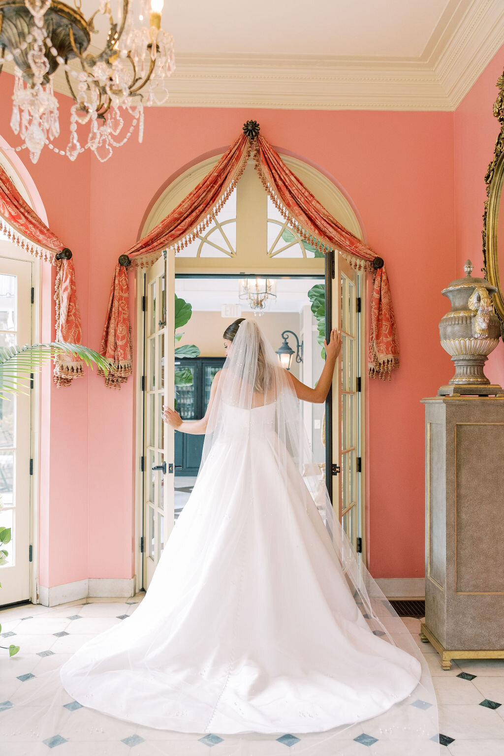 Bride stands near pink doors  at the Tate House