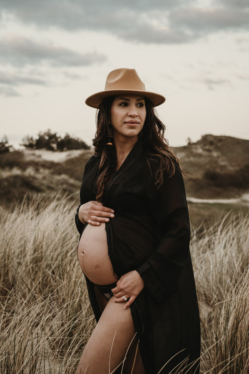 blote buik, zwangere vrouw met hoed in de duinen