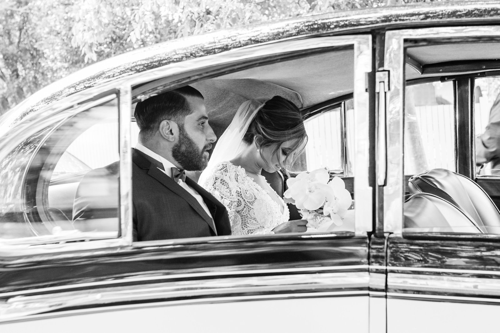 Stylish Turkish bride and groom sitting in vintage wedding car