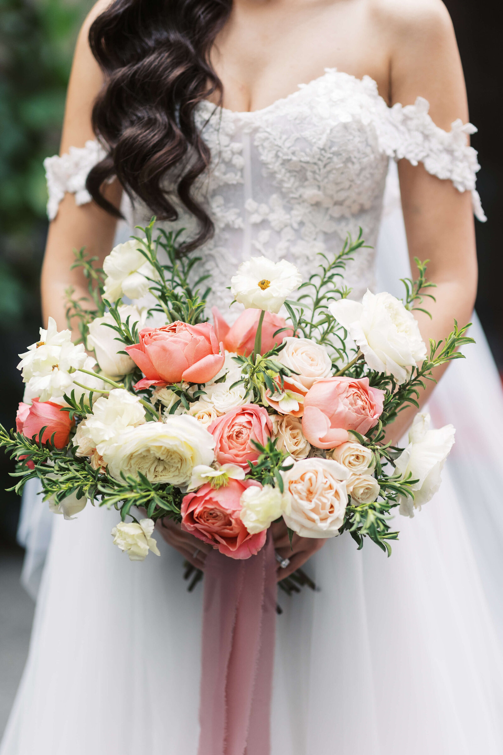 Bridal bouquet made of coral, and ivory flowers and greenery.