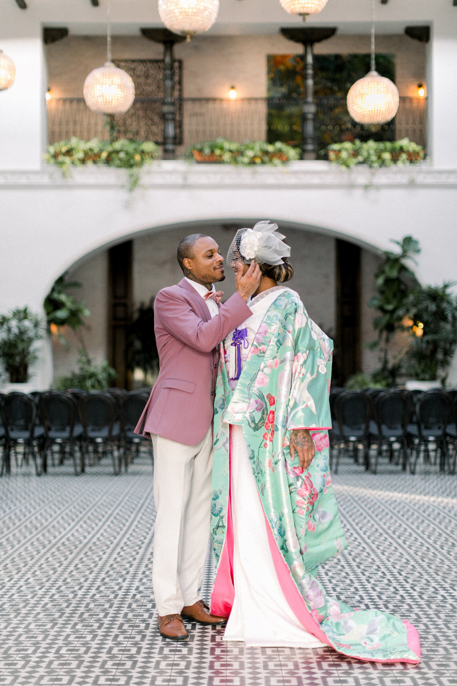 Bride in mint-green floral wedding kimono and groom in mauve suit sharing an intimate moment in the courtyard of The Ebell Club Long Beach, kimono rental wedding photography | ザ・エベルクラブ・ロングビーチの中庭で、ミントグリーンの花柄打掛を纏う花嫁とモーブ色スーツの新郎が見つめ合う着物レンタル和婚フォト