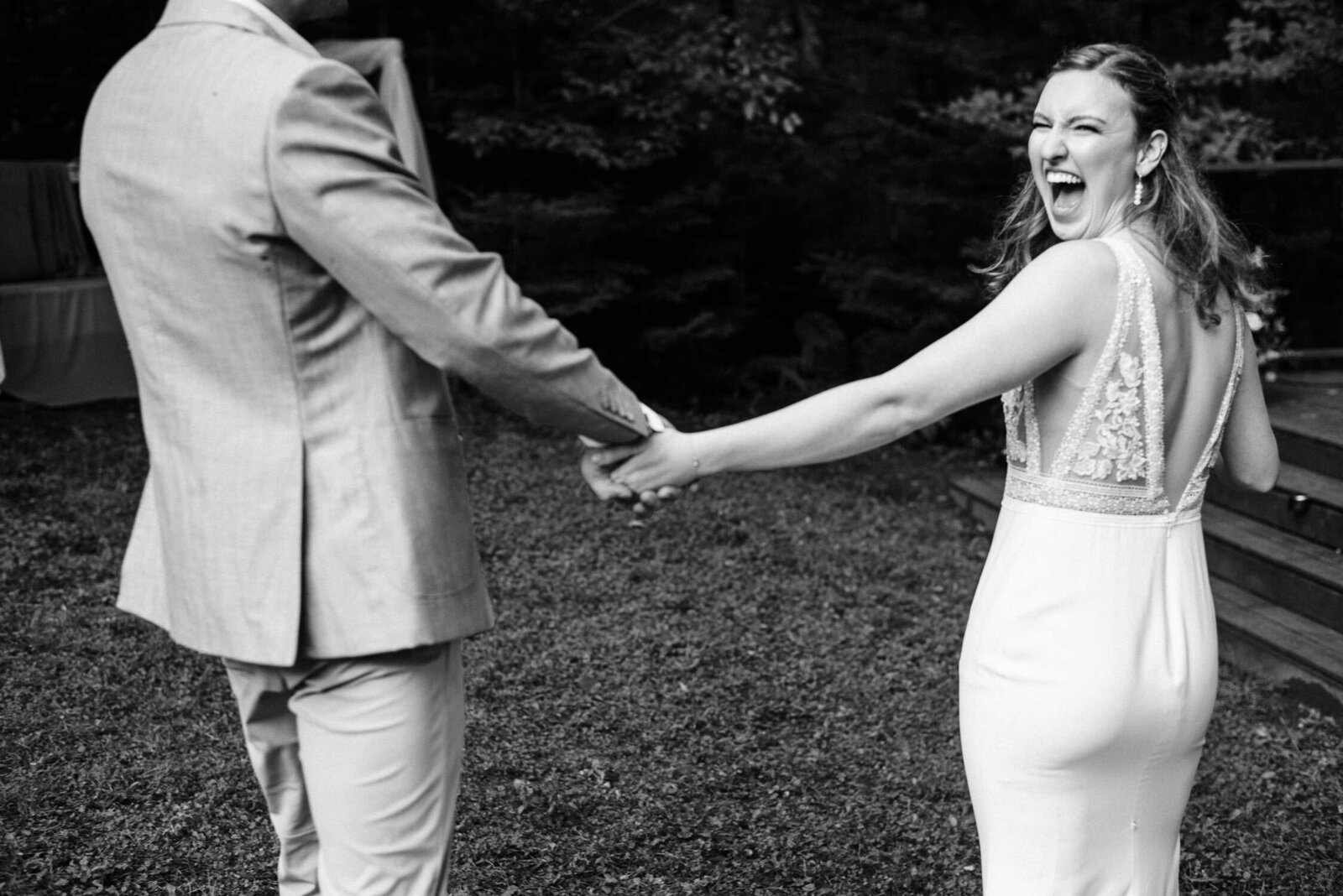 Candid moment of wedding couple holding hands and laughing.