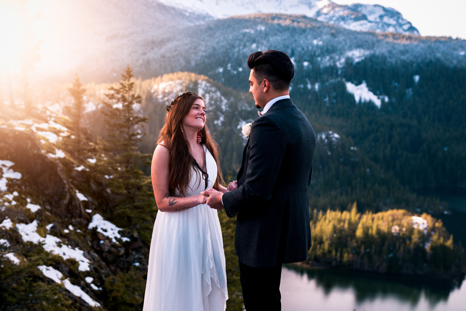 Wedding ceremony in the mountains, with couple in wedding attire, smiling at each other.