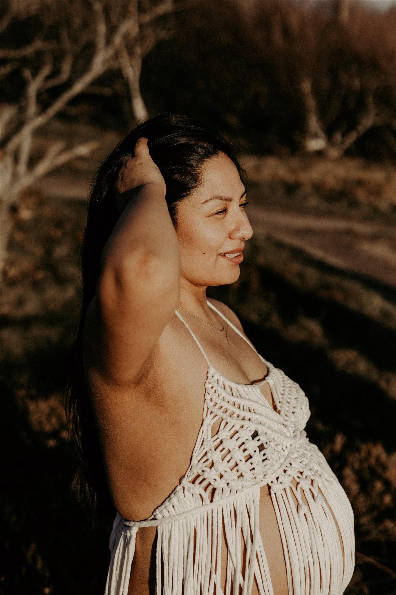 en gravidmamma drar fingrarna genom håret på ett fält