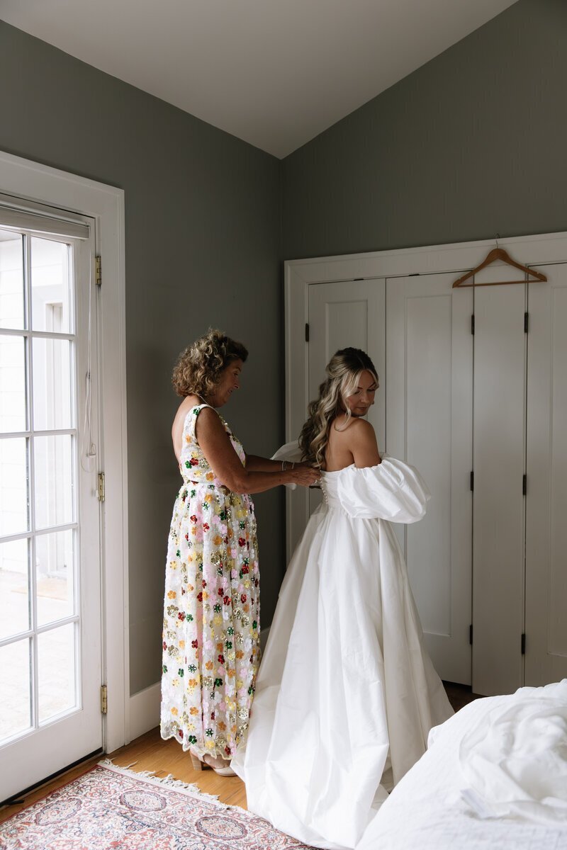 mother of bride helping bride with dress taken by idaho wedding photographer