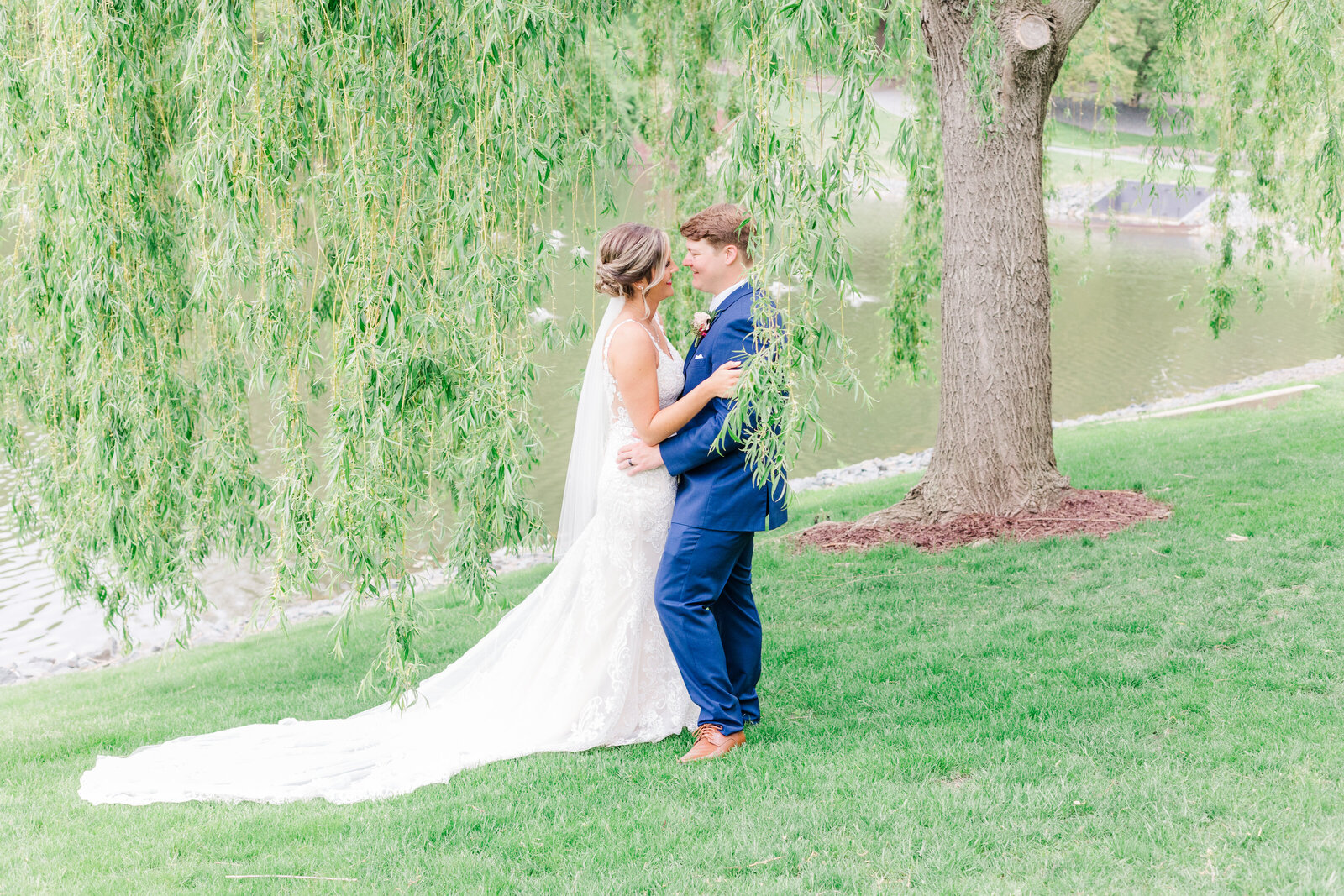 Bride and groom embrace under weeping willow