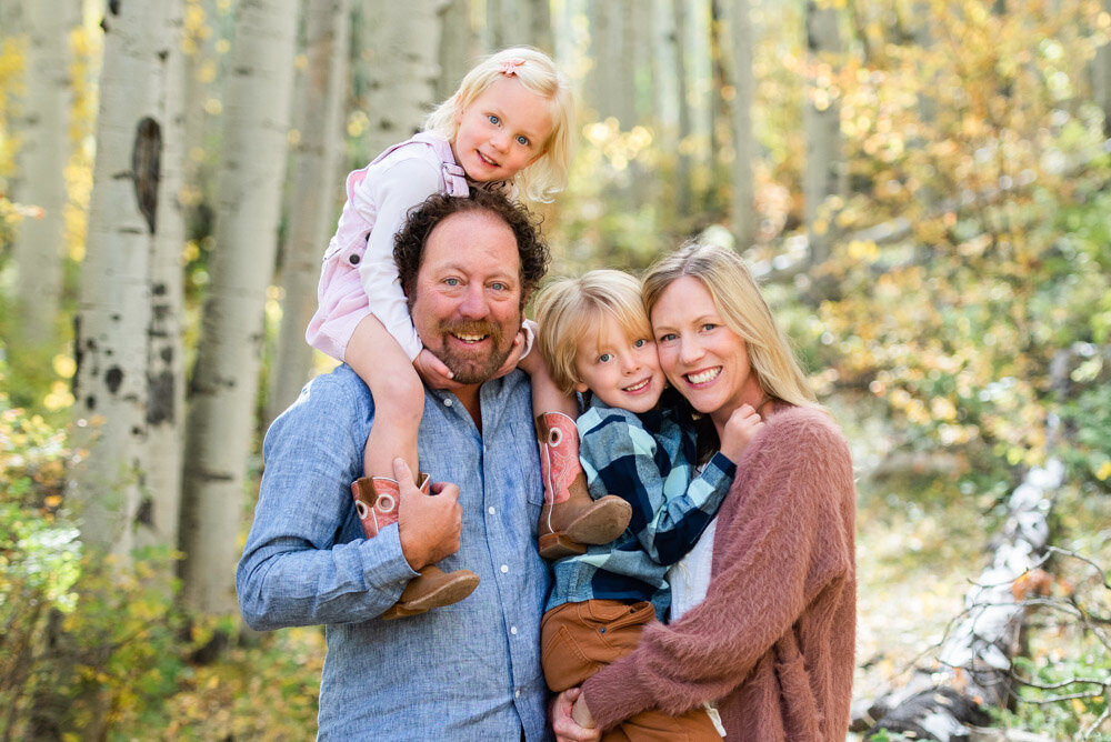 a happy family smiling at the camera in an aspen grove