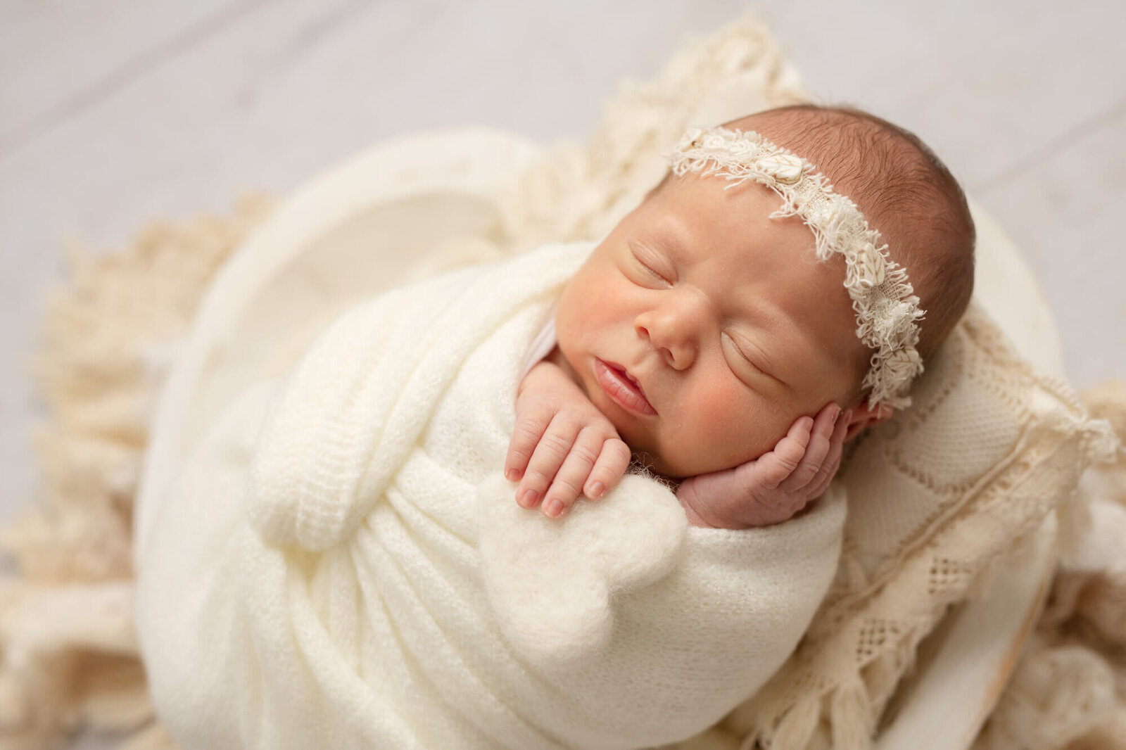 Sleeping newborn girl in white wooden white heart shaped bowl  holding felted white heart