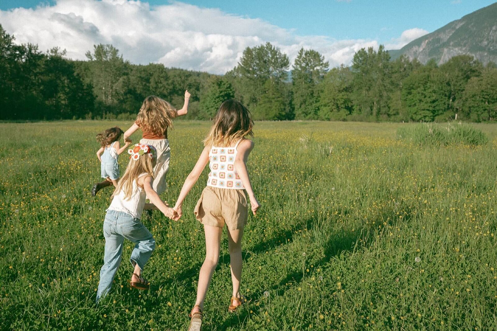 teenage girls running in outdoor field with family