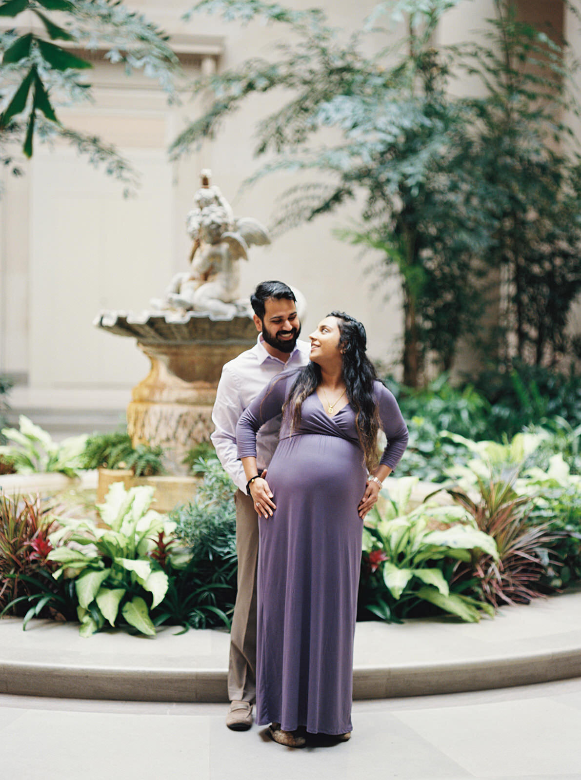 Romantic maternity couple portrait in a serene garden setting with lush greenery.