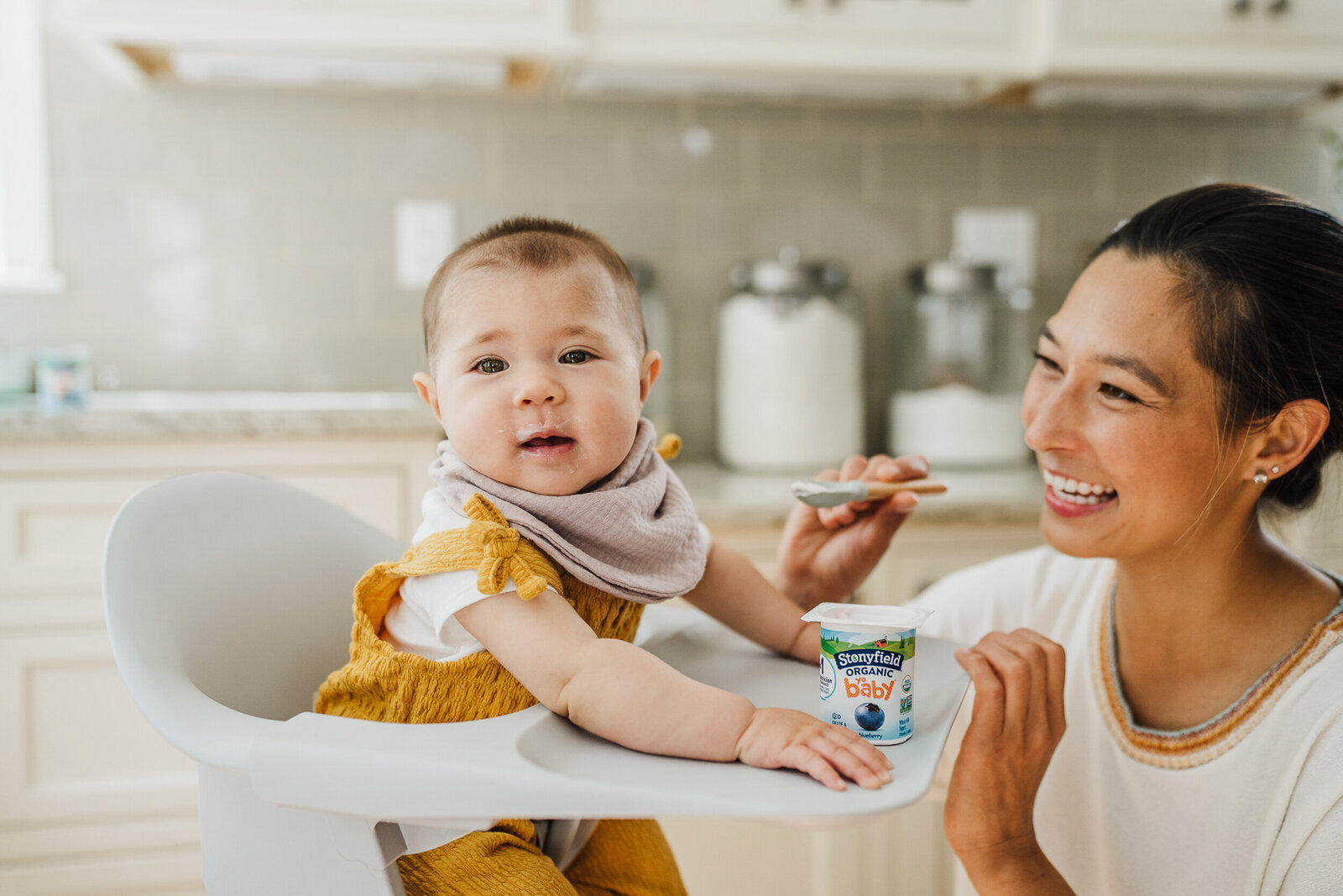 woman feeds baby yogurt during brand photoshoot in boston