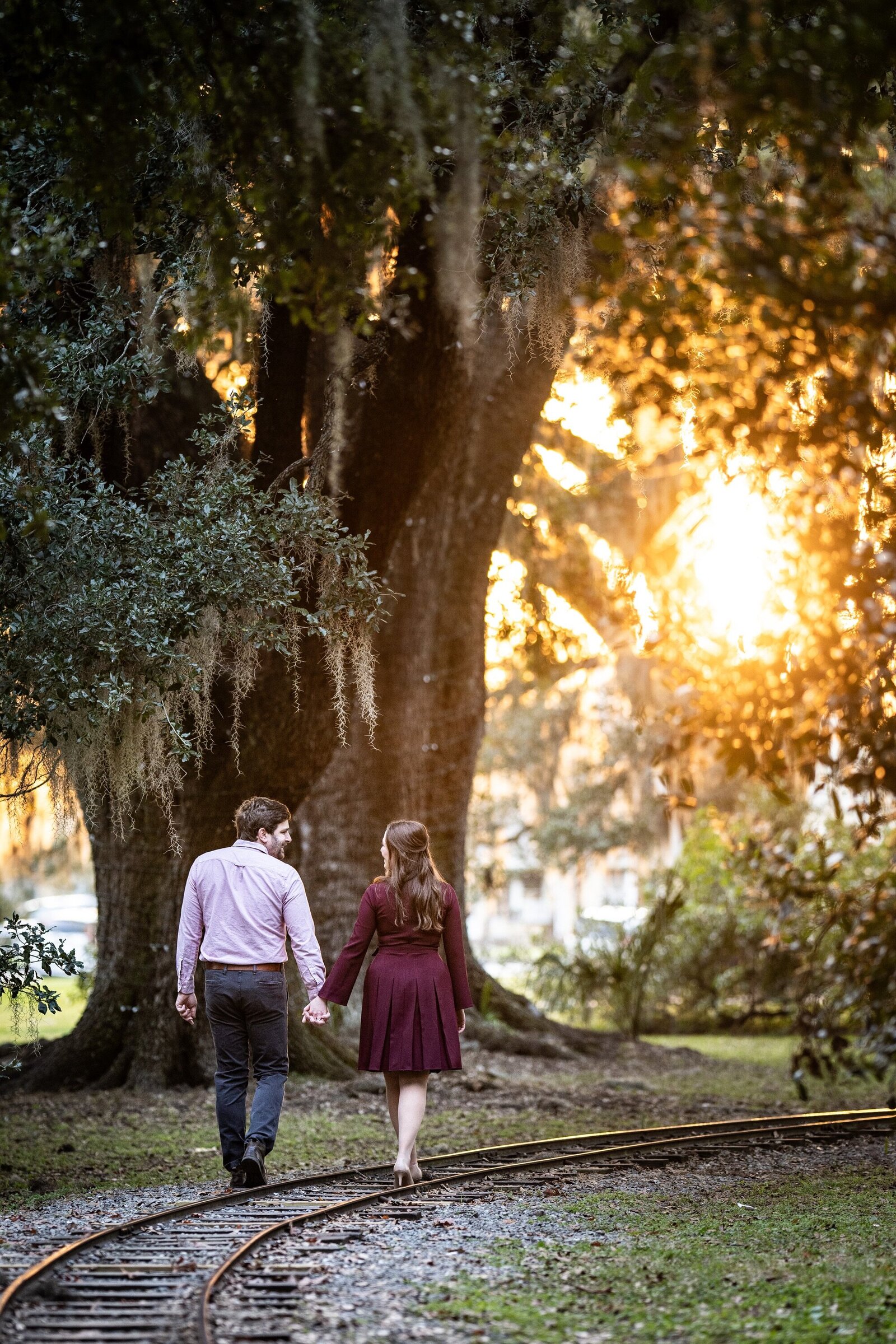 Couple walking along the railroad tracks in City Park with sunset in the background