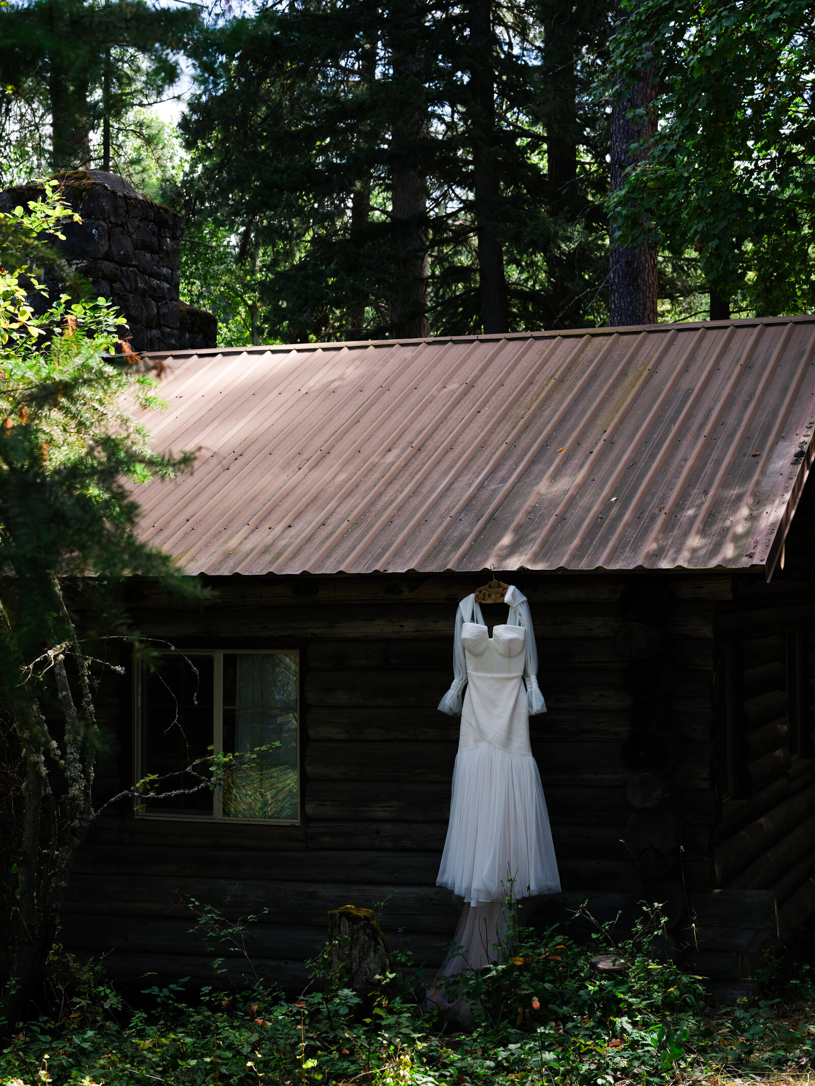 Brides dress hanging from a rustic cabin