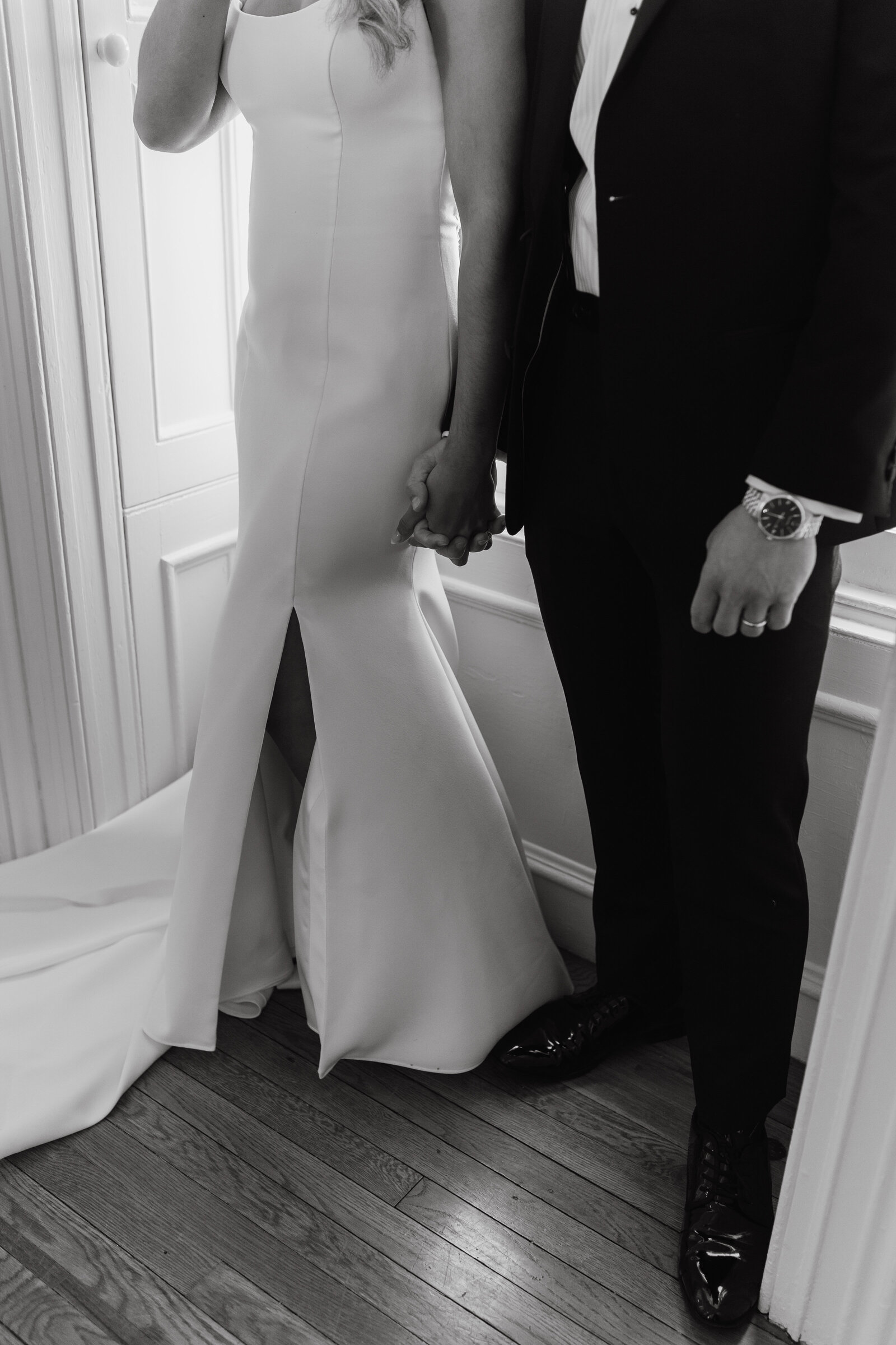 Black and white photo of bride and groom holding hands in the dressing room | Emma LeeAnn Photography